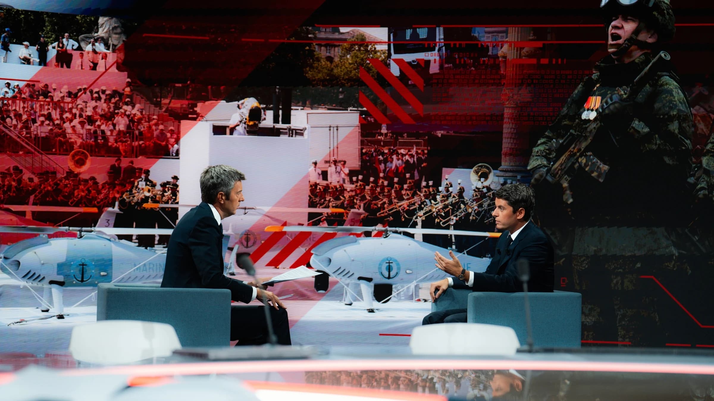 Gabriel Attal sur le plateau de BFM en train d'échanger avec un journaliste. Tout deux assis avec un air assez sérieux. 