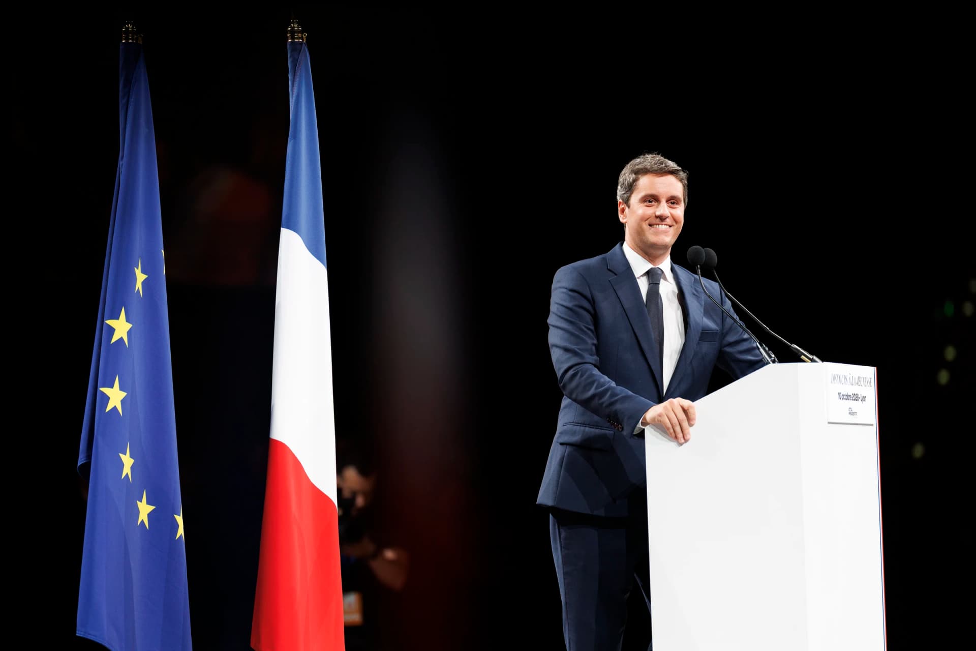 Gabriel Attal souriant à son pupitre 
