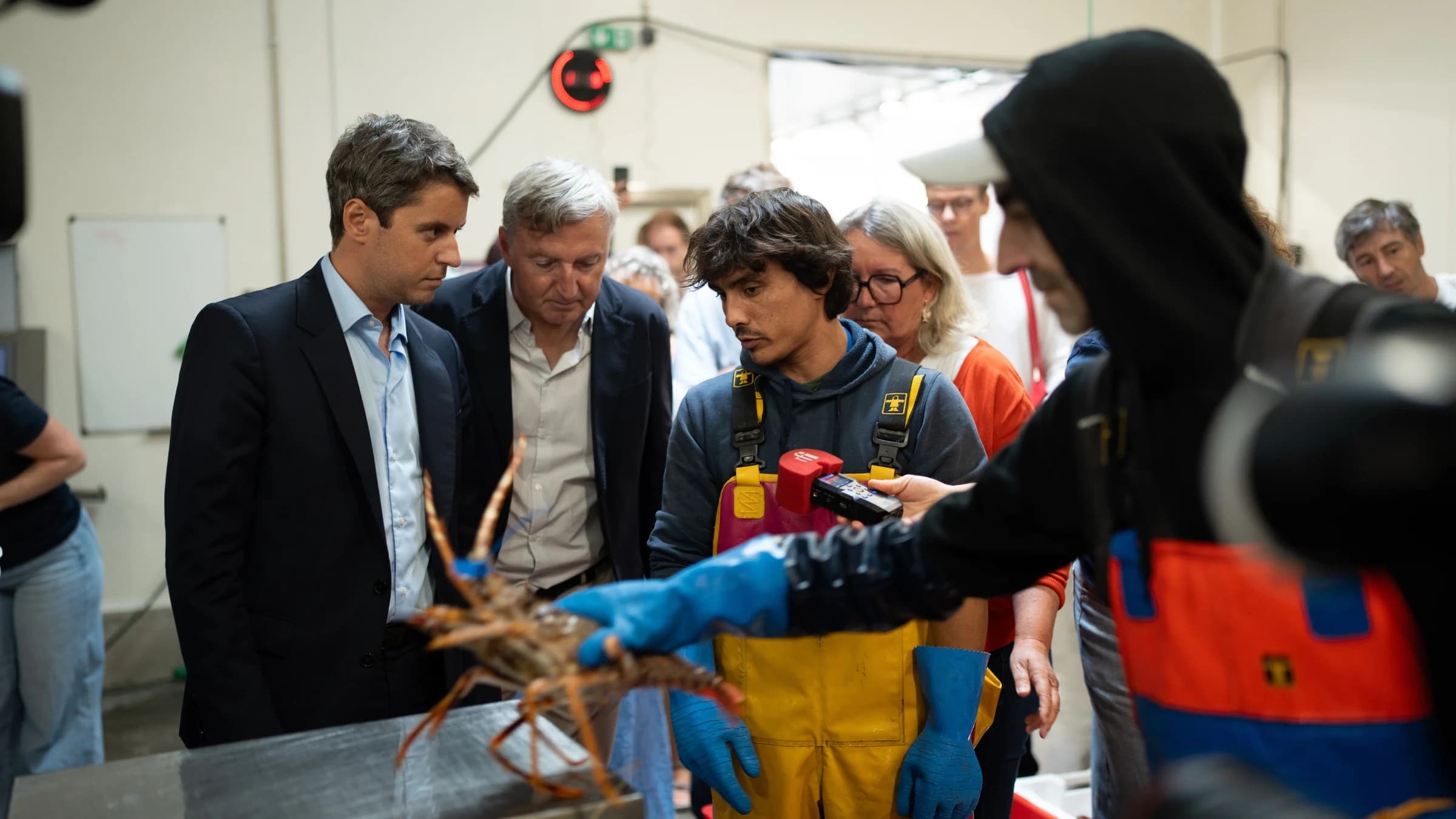 Gabriel Attal regardant un homme lors du marché à la criée