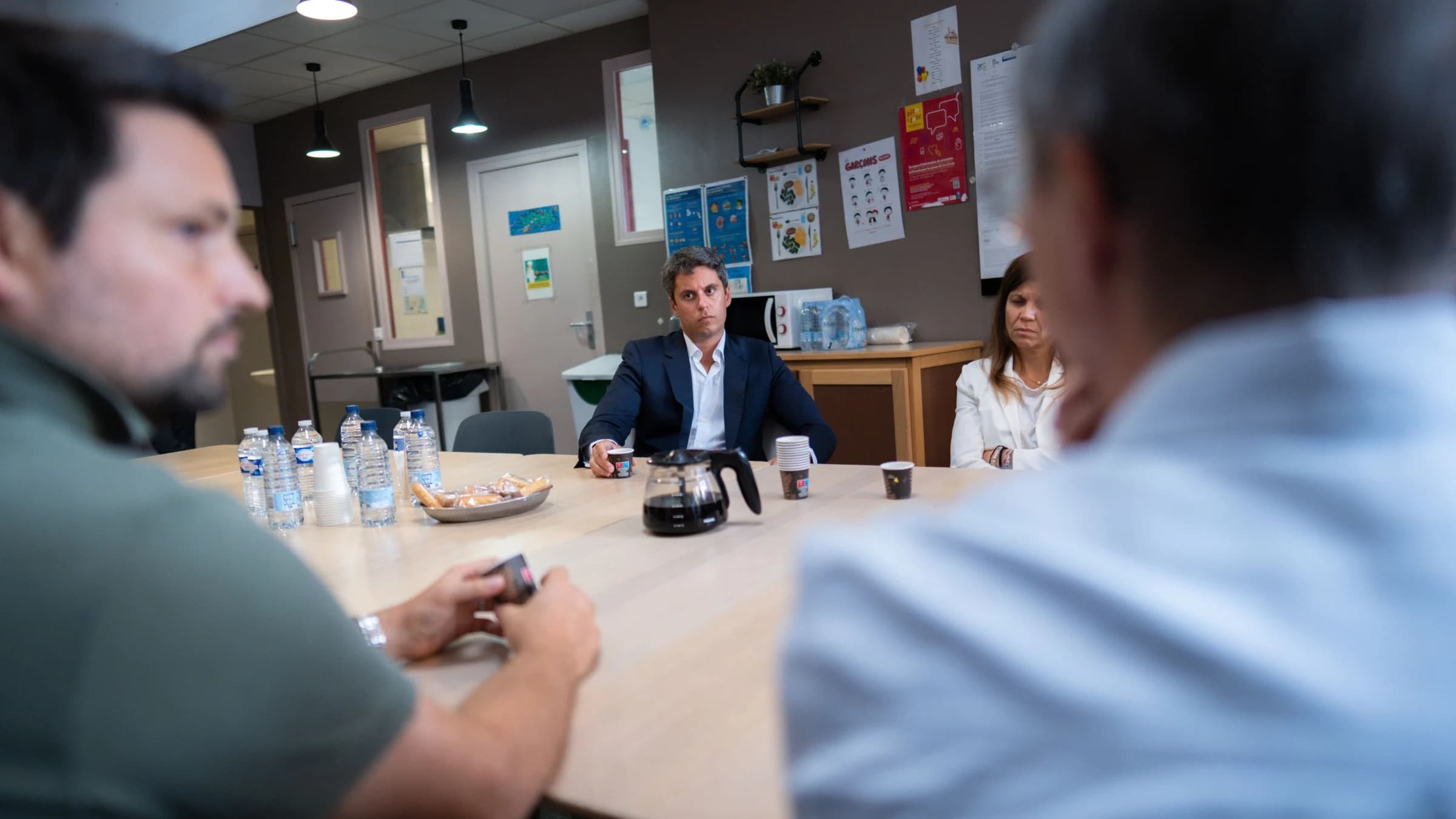 Gabriel Attal autour d'une table ronde en train d'écouter un monsieur 