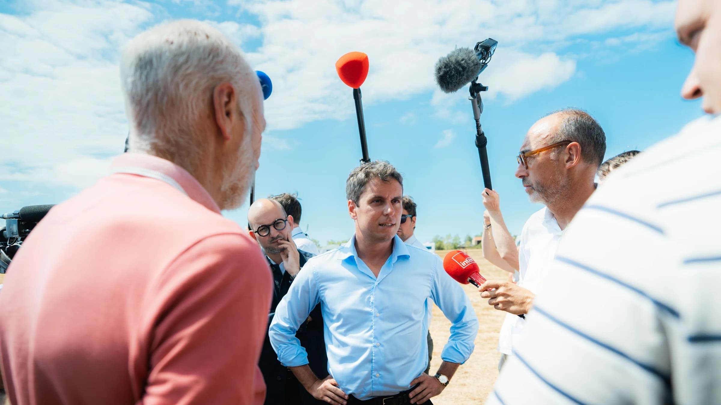 Gabriel Attal en train d'écouter deux qui parlent 