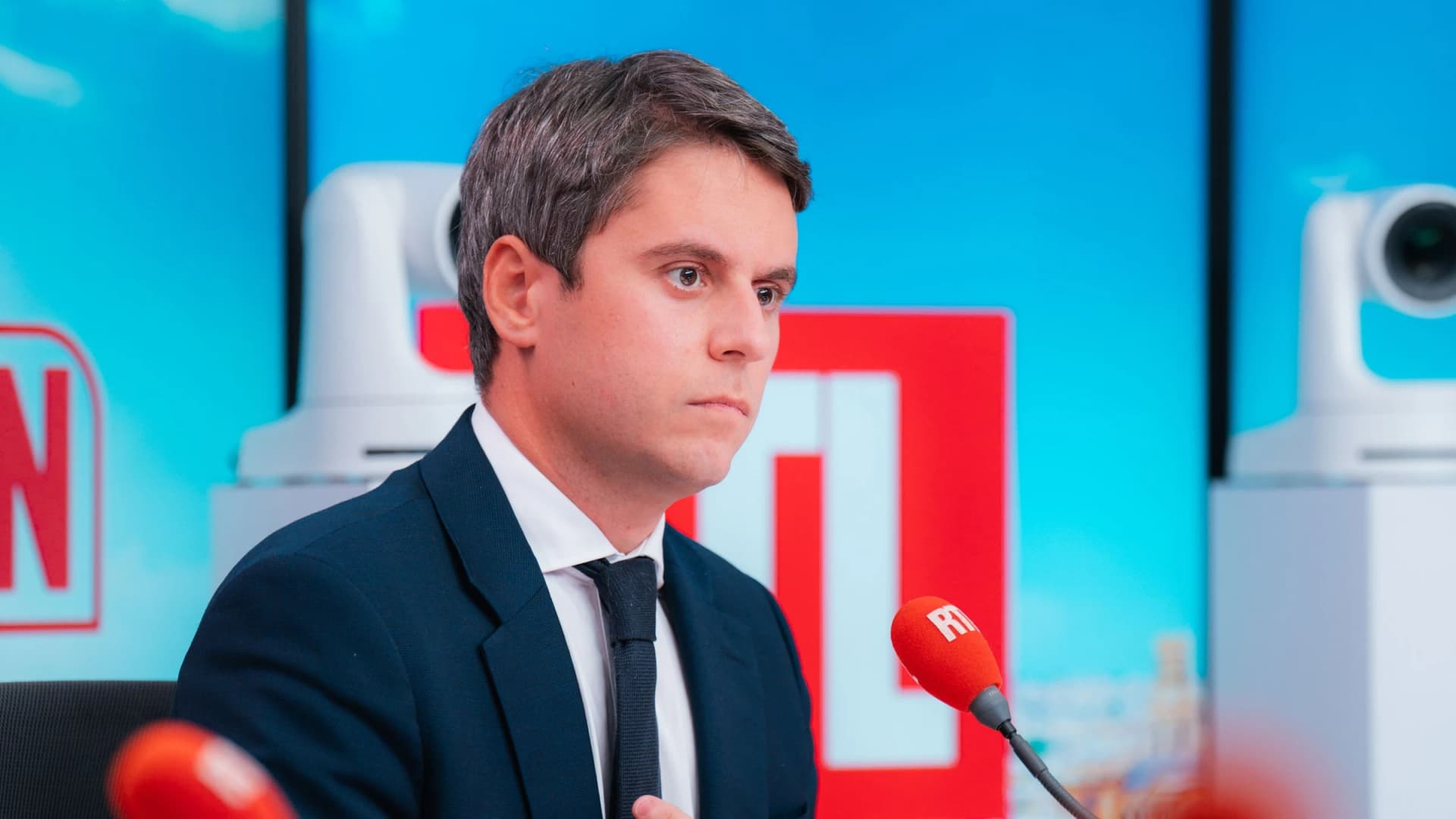 Gabriel Attal à l'écoute derrière le micro de RTL avec un regard pensant