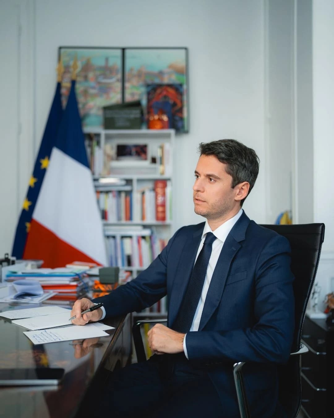 Gabriel Attal en train de réfléchir avec un drapeau français en fond 